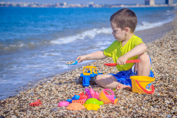 The boy plays on the beach in the toys for the sand. Children's games. Games on the beach. Galichny beach. Children's toys for sand. The baby is playing