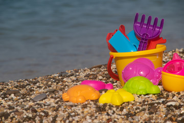 Plastic children's toys for sand on the background of the sea. Kids toys. Plastic sand toys. Bright toys. Sand construction. Children's activities. Hobbies and recreation.