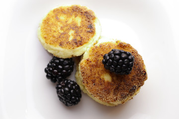 Cottage cheese pancakes or syrniki with fresh berries on plate, close up
