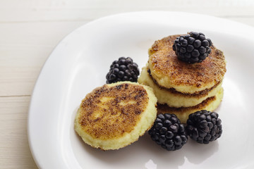 Cottage cheese pancakes or syrniki with fresh berries on plate, close up