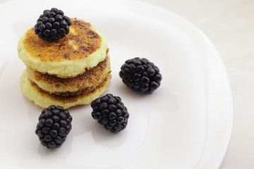 Cottage cheese pancakes or syrniki with fresh berries on plate, close up