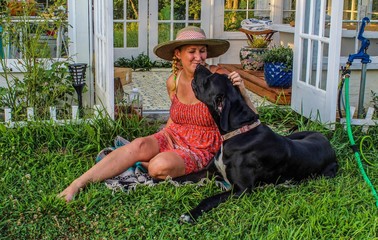 Happy and Casual Mature Woman 50-59 years old hanging out with her Great Dane in her garden in...
