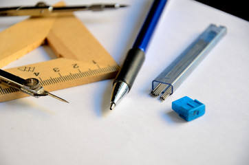 A4 sheet of paper, compasses, wooden square, mechanical pencil, graphic rods, eraser on the desk.