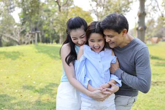 image of 3 happiness family, daughter and parents having a happy time in the park with smiling and laughing on sunny day during holiday vacation