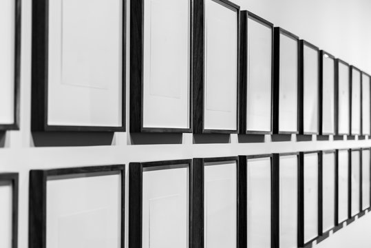 Two rows of black and white photo frames in a gallery.