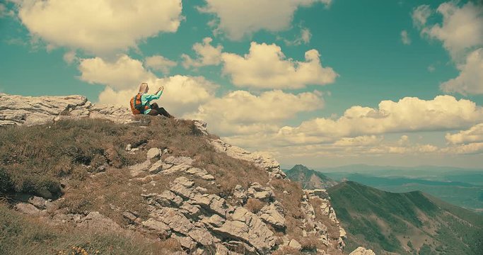 Happy traveler woman sitting on the top of mountain and shoot with her phone camera.  Beautiful mountains landscape view. 4K slow motion video