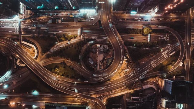 4K UHD top view time-lapse of car traffic at night on multiple lane highway, winding road, and roundabout in Hong Kong city. Commuter, city life, or land transportation concept