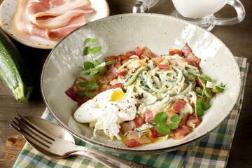 keto carbonara pasta  with spaghetti (noodles) of zucchini Low-Carb with cream, fried bacon and poached egg. decorated with pea sprouts. in a beautiful light dish. 