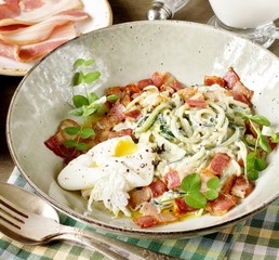keto carbonara pasta  with spaghetti (noodles) of zucchini Low-Carb with cream, fried bacon and poached egg. decorated with pea sprouts. in a beautiful light dish. 