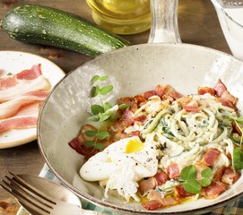 keto carbonara pasta  with spaghetti (noodles) of zucchini Low-Carb with cream, fried bacon and poached egg. decorated with pea sprouts. in a beautiful light dish. 