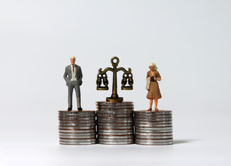 Miniature people standing on a pile of coins of the same height.