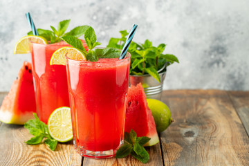 Watermelon slushie with lime and mint, summer refreshing drink in tall glasses on a light blue background. Sweet cold smoothie with copy space