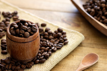 miniature barrel filled with coffee beans and wooden spoon on wooden table