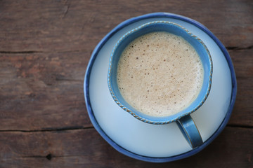 Coffee with cream in blue cup vintage mug with foam top view on the wood table