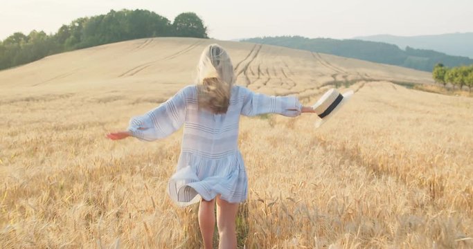 Beautiful woman walking in wheat field, sunset sun rays, Slow motion 4K.