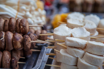 Asian food on the street, grilled corn, mushrooms on skewers, dried cheese