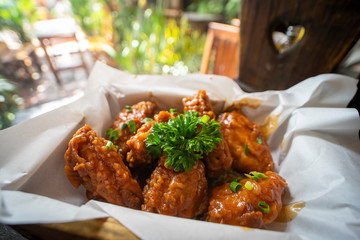 Deep fried Chicken wings with barbecue sauce on wooden tray.