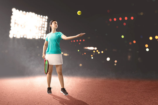 Asian woman with a tennis racket in her hands ready in serve position