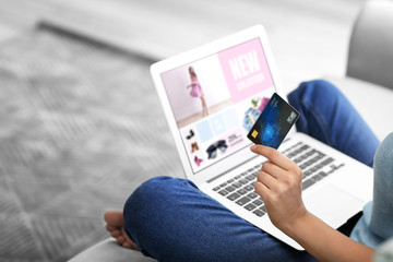 Young woman shopping online with credit card and laptop at home