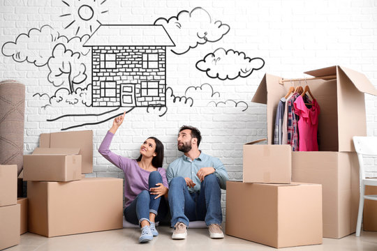 Young couple with belongings dreaming about moving into new house