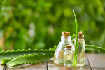 Bottles of aloe vera essential oil on wooden table