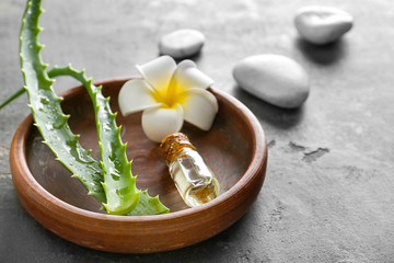 Plate with aloe essential oil on grunge background