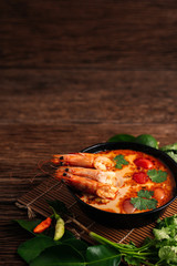 Tom Yum Goong spicy soup traditional food cuisine in Thailand on wooden background , top view, copying area, national food