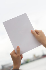 Obraz premium Kobieta trzyma puste papieru rysunku papieru papier z naturalnym tłem.