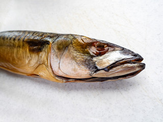 smoked fish mackerel lying on a white cutting Board, close-up