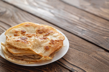 on a plate are fried bread cakes, wooden textured table.