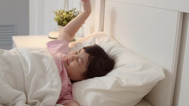 Young Asian girl wake up at home. Asia japanese woman child kid relax rest after sleep all night lying on bed, feel comfort and calm in bedroom at home in the morning concept. Slow motion shot.