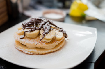 two waffles and banana with chocolate sauce on wooden plate