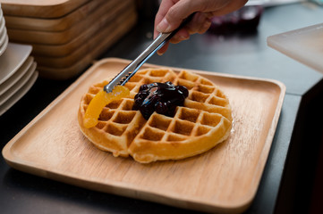 waffles topping peach and ice cream on wooden plate