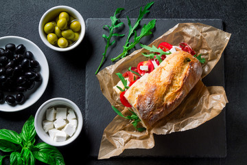 Sandwich with jamon, feta cheese and arugula on a black background top view