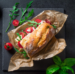 Sandwich with jamon, feta cheese and arugula on a black background top view