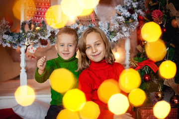 Fototapeta na wymiar happy brother and sister hugging near Christmas tree