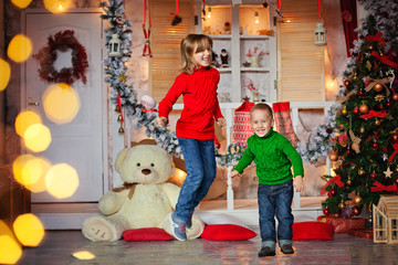 brother and sister jumping around the Christmas tree