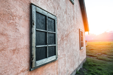 Fototapeta na wymiar Old rusty wooden frame on stone painted pink wall on mountain house at sunset time