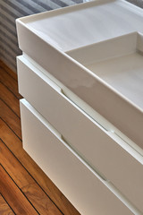 Wall mounted bathroom vanity in luxury bathroom with teak floor and striped tiles. Stylish interior of modern bathroom. Details furniture