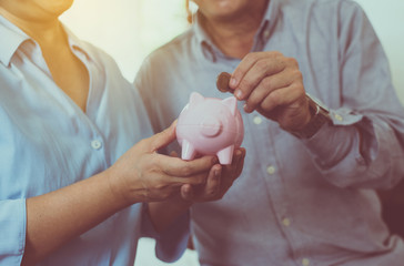 Senior couple hands putting coin to piggy bank for retirement together,Saving money concept