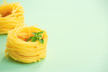Traditional Italian fettuccine pasta and basil on a light green background. Space for text.