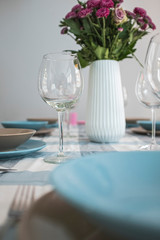 Cutlery, dishes and empty wineglasses and decoration flower bouquet on a served restaurant table