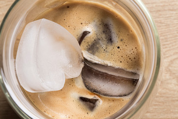 Espresso coffee with heart shaped ice rocks on a wooden background