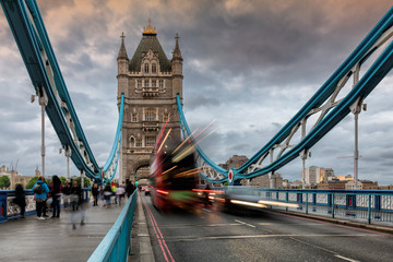 Tower Bridge in London UK in evening with moving red double-decker bus leaving light traces, United Kingdom.