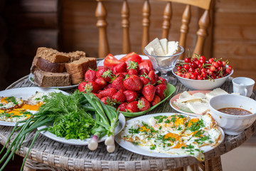 Delicious and healthy breakfast on the table , closeup. Fried eggs, bread, greens, vegetables, berries and cheese serving for breakfast