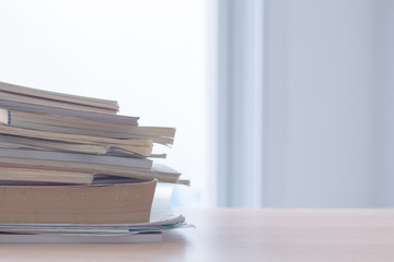 Stack of book and document on table by the window.