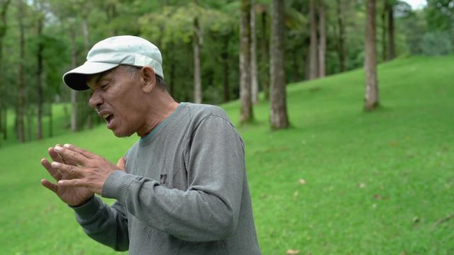 old asian man sneezing having a flu while in the park