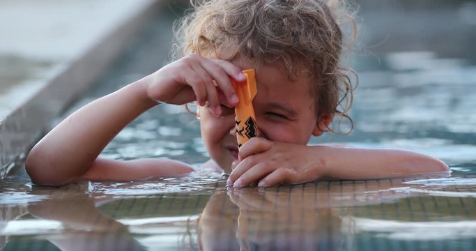 Shy bashful baby boy hiding from camera inside swimming pool water