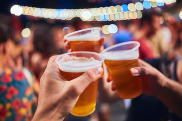 Friends drinking beer at night with de-focused lights in the background. Shallow focus.