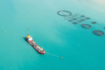Aerial view cargo tanker moored in the bay, near the farm for growing fish.